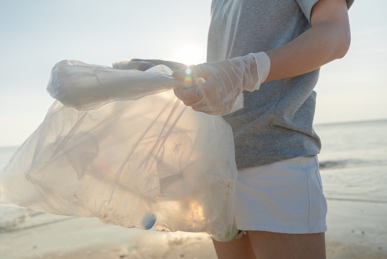 Globale Verantwortung, Mensch sammelt Plastikmüll am Meer, 